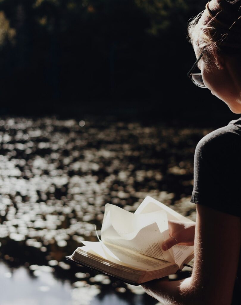 Girl Reading a Book by a Lake